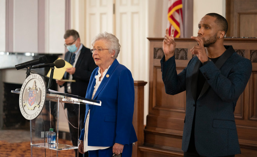Gov. Kay Ivey speaks at a press conference in Montgomery Thursday with state health officer Scott Harris (behind her), as the state emergency orders on COVID-19 were extended  until March 5. A sign language interpreter also signed her remarks.
