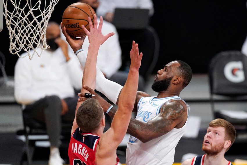 Los Angeles Lakers forward LeBron James, center, shoots as Washington Wizards center Moritz Wagner, left defends along with forward Davis Bertans during the first half of an NBA basketball game Monday, Feb. 22, 2021, in Los Angeles. (AP Photo/Mark J. Terrill)