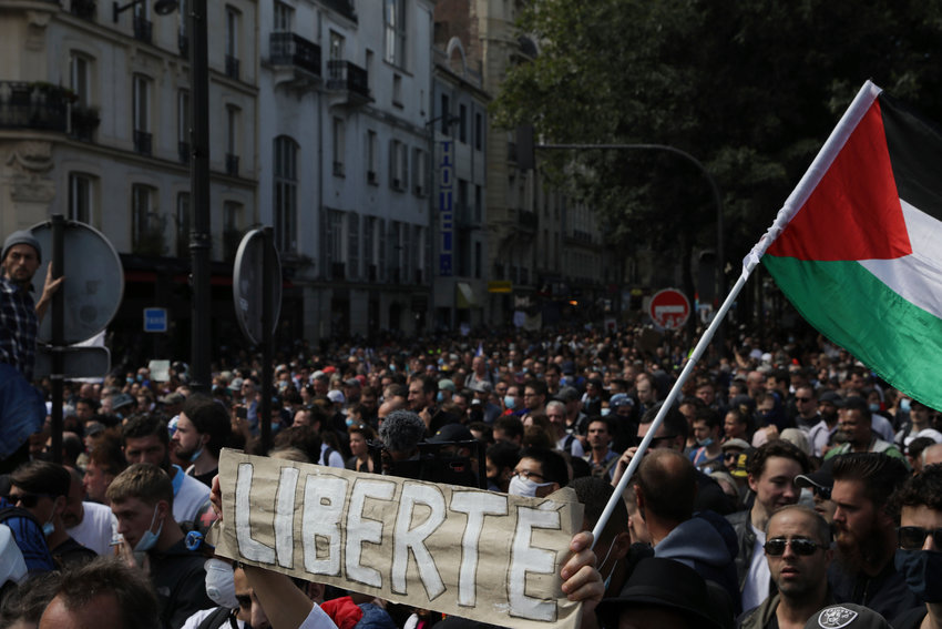 Protestors hold up a banner which reads 'freedom' in French during a demonstration in Paris, France, Saturday, July 31, 2021. Demonstrators gathered in several cities in France on Saturday to protest against the COVID-19 pass, which grants vaccinated individuals greater ease of access to venues. (AP Photo/Adrienne Surprenant)