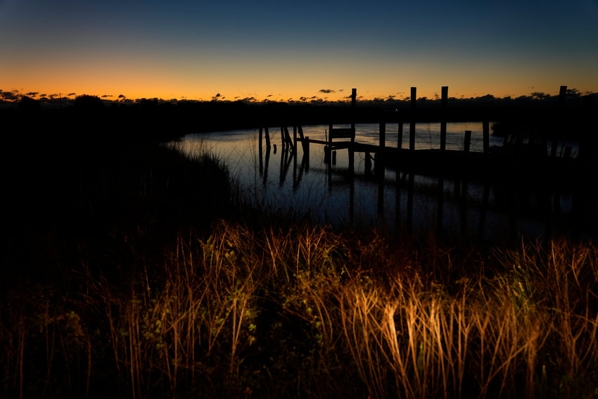 Dawn breaks over marshland surrounding a dock, on St. Helena Island, S.C., Sunday, Oct. 31, 2021. In some parts of the U.S., the risks from climate change have intensified to the point that communities are considering abandoning their land to nature. One strategy that is gaining traction is so-called managed retreat, which is the planned relocation of vulnerable communities. (AP Photo/Rebecca Blackwell)