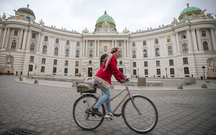 A woman rides a bicycle along an empty street in Vienna, Austria, Monday, Nov. 22, 2021. Austria went into a nationwide lockdown early Monday to combat soaring coronavirus infections, a step being closely watched by other European governments struggling with national outbreaks that are straining health care systems.(AP Photo/Vadim Ghirda)