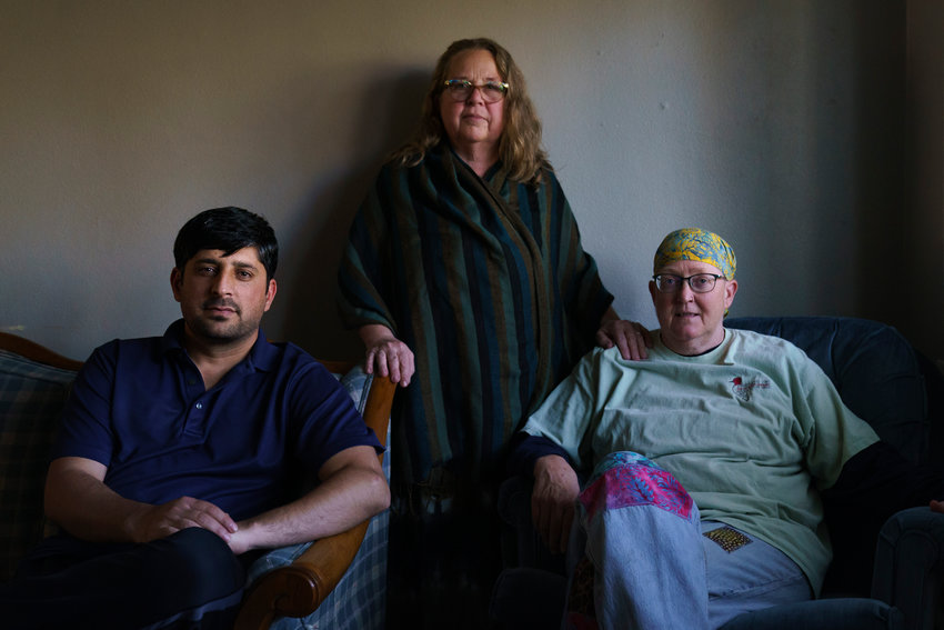 Ihsanullah Patan, left, a horticulturist and refugee from Afghanistan, sits for a portrait with Caroline Clarin, right, whom he worked with in Afghanistan, and her wife, Sheril Raymond, at his home in Fergus Falls, Minn., Friday, Oct. 29, 2021. A U.S. Department of Agriculture adviser in Afghanistan, Clarin along with her wife have been using their own time and money to get Afghans who worked for her program out of the country. Those who have started their life in the remote town of Fergus Falls near the North Dakota border say they consider them family. (AP Photo/David Goldman)