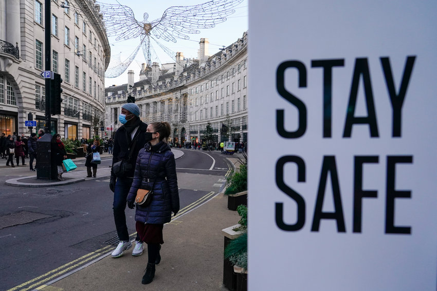 People wear face masks as they walk past a sign reading &lsquo;Stay safe&rsquo;, in Regent Street, in London, Sunday, Nov. 28, 2021. Britain's Prime Minister Boris Johnson said it was necessary to take &ldquo;targeted and precautionary measures&rdquo; after two people tested positive for the new variant in England. He also said mask-wearing in shops and on public transport will be required. (AP Photo/Alberto Pezzali)