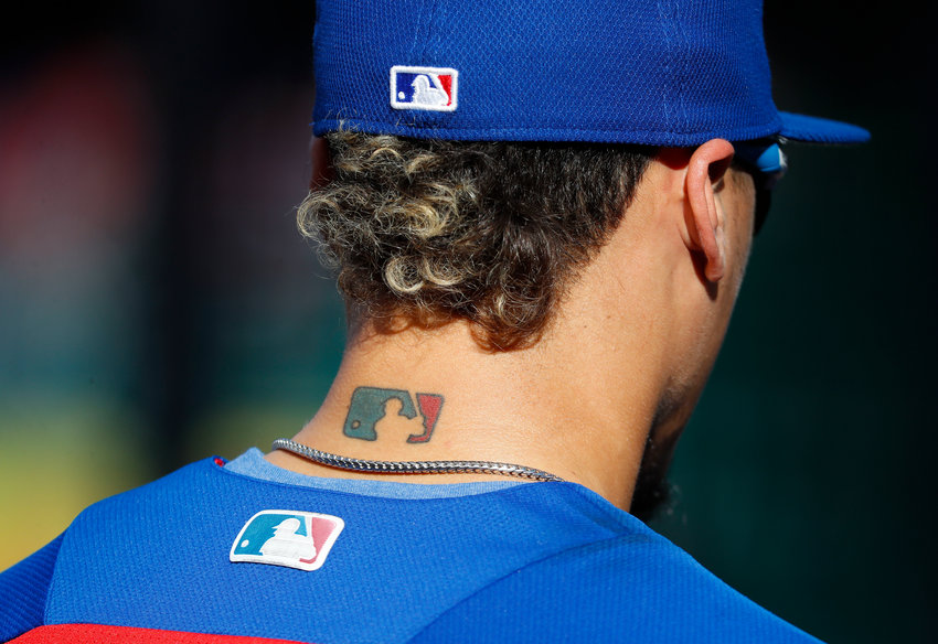 Chicago Cubs' Javier Baez sports a MLB- logo tattoo on the back of his next as he waits to take batting practice before Game 2 of baseball's National League Division Series against the Washington Nationals at Nationals Park, Saturday, Oct. 7, 2017, in Washington. (AP Photo/Pablo Martinez Monsivais)