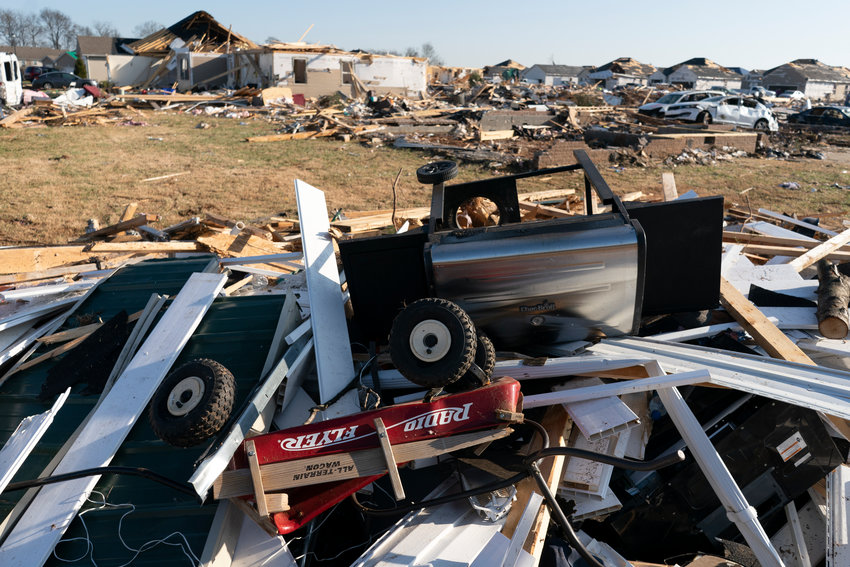 A Radio Flyer wagon lies among debris along Moss Creek Avenue Tuesday, Dec. 14, 2021, in Bowling Green, Ky. When a tornado touched down in Bowling Green in the middle of the night, its violence was centered on a friendly subdivision. Fourteen people died in a few blocks, 11 of them on a single street, Moss Creek Avenue. Entire families were lost, between them seven children, two of them infants. (AP Photo/James Kenney)