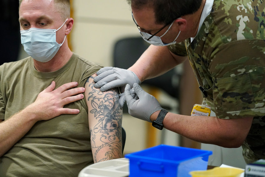 FILE - Staff Sgt. Travis Snyder, left, receives the first dose of the Pfizer COVID-19 vaccine given at Madigan Army Medical Center at Joint Base Lewis-McChord in Washington state, Dec. 16, 2020, south of Seattle. The Army says 98% of its active duty force had gotten at least one dose of the mandatory coronavirus vaccine as of this week&rsquo;s deadline for the shots.  (AP Photo/Ted S. Warren, File)