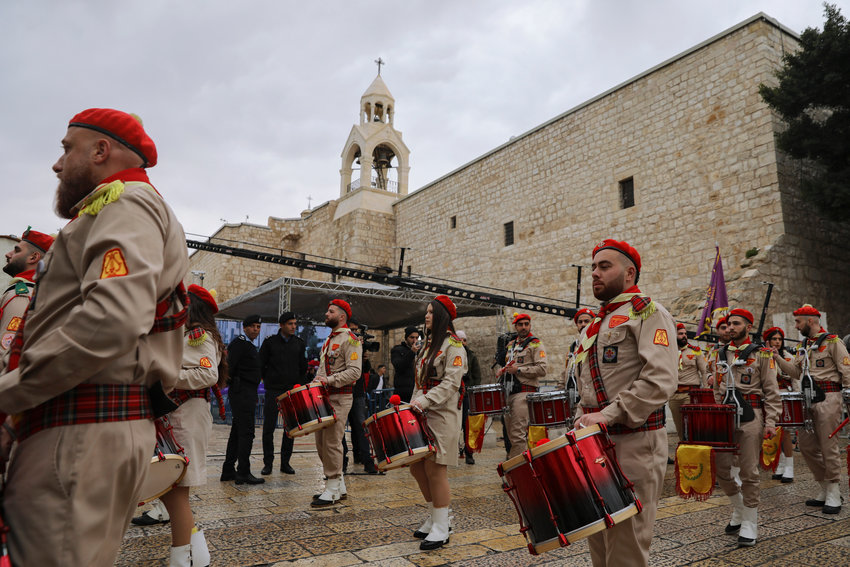 Palestinian scout bands parade through Manger Square at the Church of the Nativity,  traditionally believed to be the birthplace of Jesus Christ, during Christmas celebrations, in the West Bank city of Bethlehem, Friday, Dec. 24, 2021. The biblical town of Bethlehem is gearing up for its second straight Christmas Eve hit by the coronavirus with small crowds and gray, gloomy weather dampening celebrations Friday in the traditional birthplace of Jesus. (AP Photo/Mahmoud Illean)