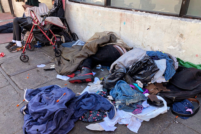 FILE - People sleep near discarded clothing and used needles on a street in the Tenderloin neighborhood in San Francisco, on July 25, 2019.  The San Francisco Board of Supervisors approved an emergency order the mayor wants to tackle an opioid epidemic in its troubled Tenderloin district.  (AP Photo/Janie Har, File)