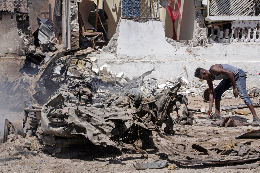 A man sifts through wreckage at the scene of a blast in Mogadishu, Somalia Wednesday, Jan. 12, 2022. A large explosion was reported outside the international airport in Somalia's capital on Wednesday and an emergency responder said there were deaths and injuries. (AP Photo/Farah Abdi Warsameh)