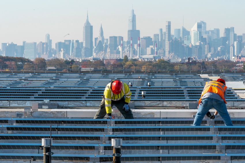 Framed by the Manhattan skyline electricians with IBEW Local 3 install solar panels on top of the Terminal B garage at LaGuardia Airport, Tuesday, Nov. 9, 2021, in the Queens borough New York. The solar farm installation under construction on the roof is expected to power the garage and west end of the airport will be completed in the Spring of 2022. (AP Photo/Mary Altaffer)