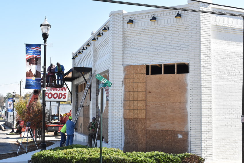 Workers install modern awnings recently as part of the redevelopment of the old TOP Dollar store in downtown Jasper.