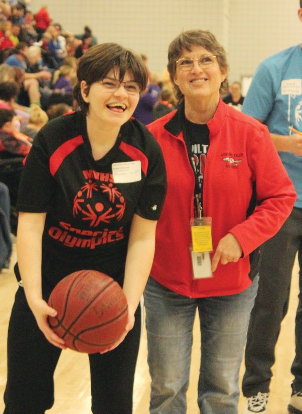 Kaylee Holcomb tries her best to make a basket as one of her teachers cheers her on in the basketball Special Olympics competition.