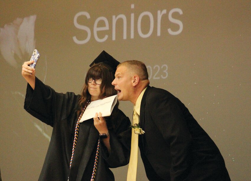 A few seniors stopped to take a selfie on the stage in graduation swag during the 2023 graduation ceremony in Woodbine.