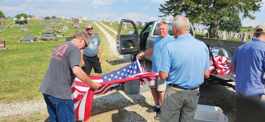 Pictured folding the flag, from left to right: Rick Vogt, Philip Leinen, Ace Ettleman and Timothy Ettleman.