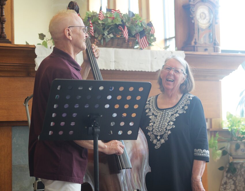 Delores Dorland (right) teaches Library Director Bruce Kocher (left) to play the bass.