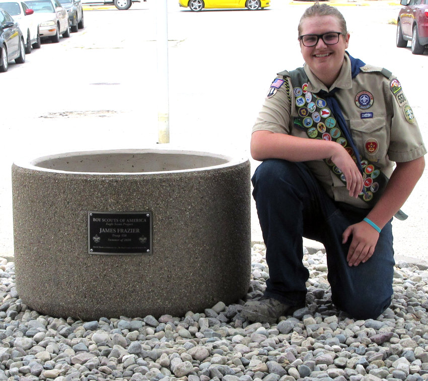 James Frazier poses at his completed project, which includes a large planter with a plaque.