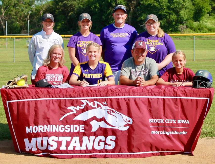 Logan-Magnolia senior Amelia Evans (front, second from left) is all smiles after signing her letter of intent to continue playing college softball at Morningside College (Sioux City) on June 23 before the start of the final home regular season contest.  She is seated with her family in the front row, from left, Kelly Evans, Amelia Evans, Jamie Evans, Kennedy Evans.  Standing in back include, from left, Morningside Softball Coach Brooke Pruner, Logan-Magnolia High School Softball Coaches Blaire Kuhlman, Rick McHugh, Megan Dunn.