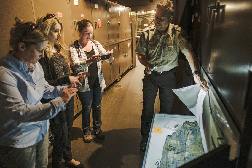 DeSoto National Wildlife Refuge curator Bill Cantine shows a rain jacket recovered from the Steamboat Bertrand to U.S. Fish and Wildlife Service cultural conference members during their tour through the Bertrand exhibit on Sept. 13.
