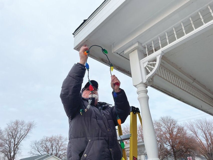 Fonley Allen hangs lights on the Dougal House as a member of the Dunlap Historical Society ahead of Dunlap Shop Hop on Friday, Nov. 18.