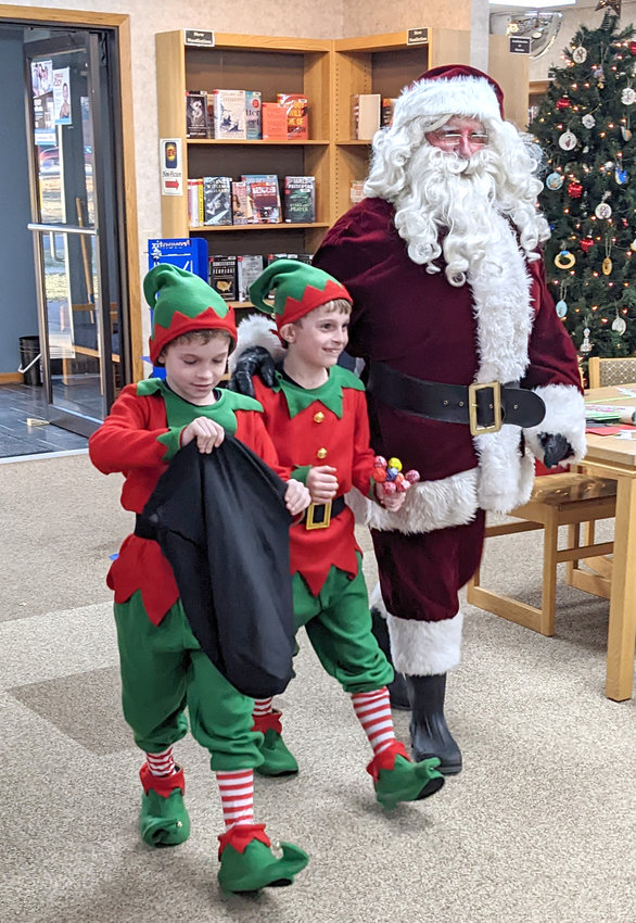 Santa and his elves (Ben and Graham LeFebvre) stopped by the Christmas party at the Mapleton library on Dec. 10.