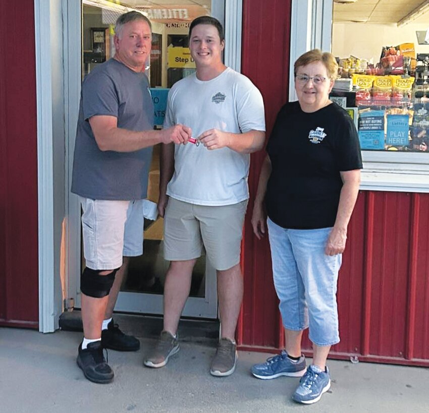 Colin Garrett (middle) officially began overseeing operations of the company on July 1. He's pictured receiving the key from Ace and Marilyn Ettleman.