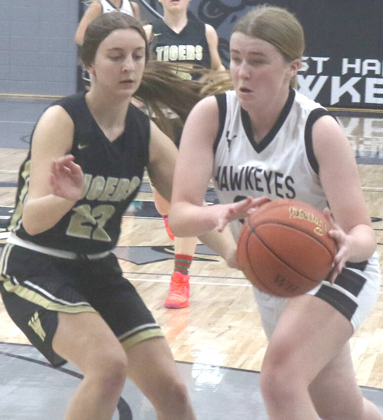 West Harrison's Rylee Evans (with ball) drives past Woodbine's Taylor Hoefer (21) in Rollling Valley Conference play on Dec. 21 at Mondamin.