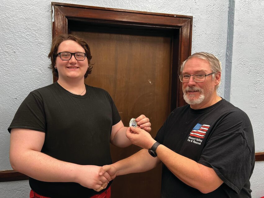 Chief Forest Dooley (right) presents Carter Coyle with a cadet badge.