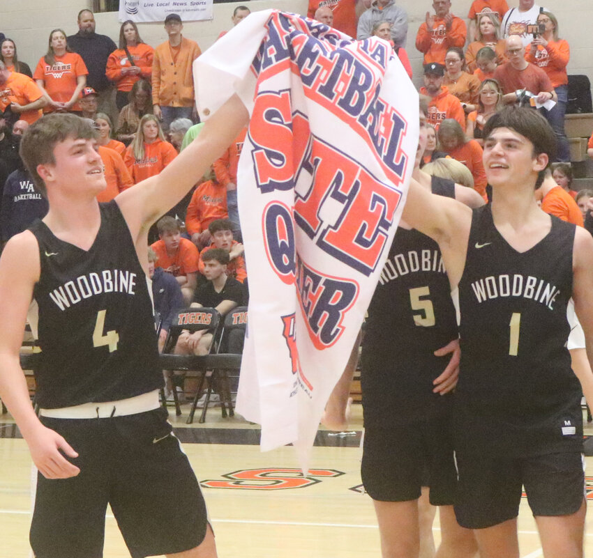 Woodbine's Brody Pryor (4) and Carter Gruver (1) raise the school's first Boys State Basketball Tournament banner since 1996.