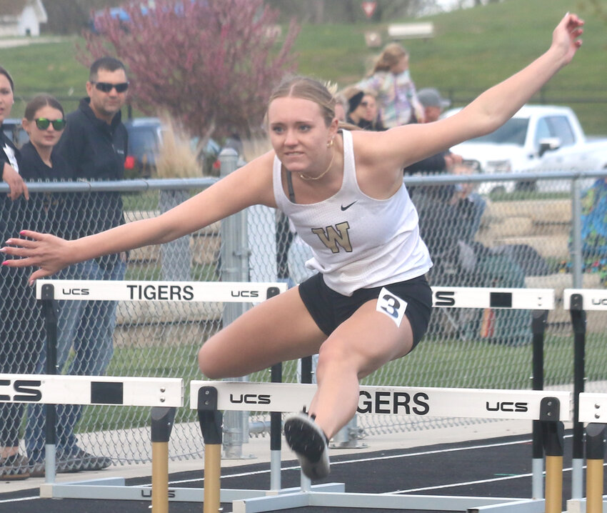 Woodbine's Kylie Neligh clears the hurdle during the shuttle hurdle relay at the Woodbine Invitational on April 25 in Woodbine.