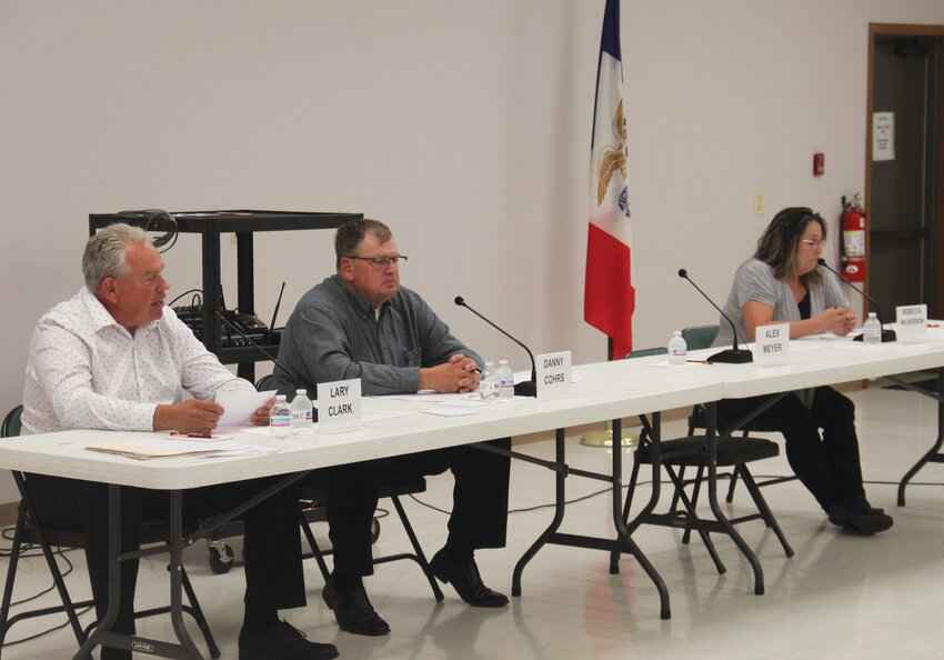 Lary Clark (left) speaks during a candidate forum as Danny Cohrs (middle) and Rebecca Wilkerson (right) listen on.