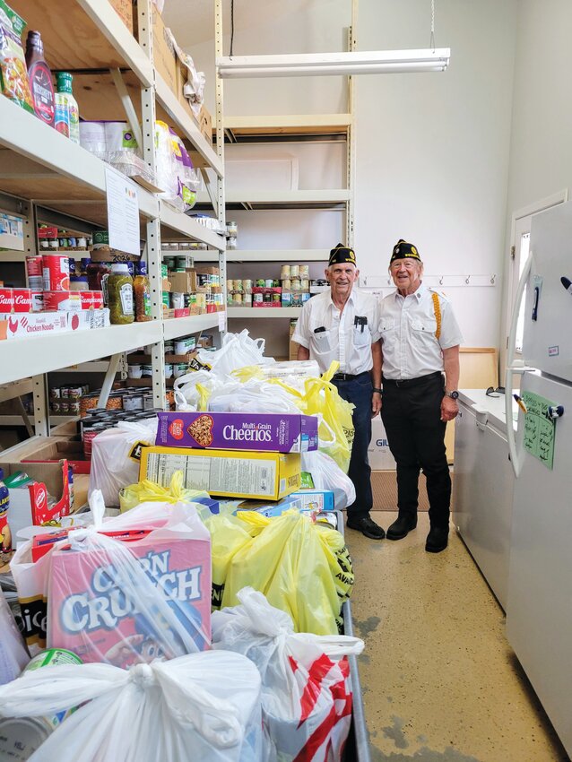 Legionnaire John Kerger (left) and Steve Harrington (right) stand amidst the donations after the food drive.