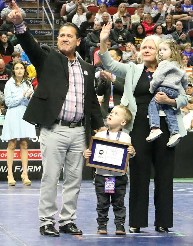 Rod Earleywine (left) points toward his family and friends who celebrated his induction into the Iowa High School Wrestling Hall of Fame on Feb. 22 at Wells Fargo Arena in Des Moines.  He is shown wiht his wife, Molly, and their grandchildren.