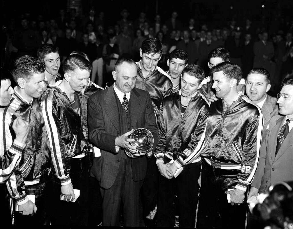 University of Kentucky basketball coach Adolph Rupp and his team admire the NCAA basketball title cup after defeating Oklahoma A&M 46-36 in Seattle in March 1949, which was the first year of the AP men's basketball poll. The Associated Press is ranking all 204 college basketball programs that have appeared in the poll since its inception 75 years ago. (AP Photo/Paul Wagner)