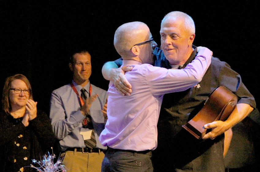 North Scott High School principal Shane Knoche embraces Richard Erps, who retired after 42 years as high school custodian.