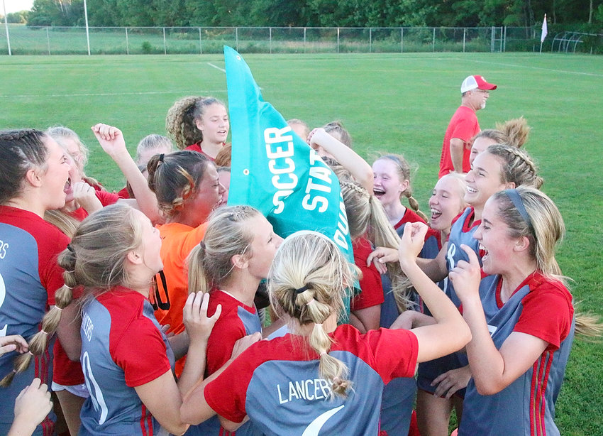 Members of North Scott's girls' soccer team were all smiles after they collected their state qualifier banner from athletic director Jason Schroeder.