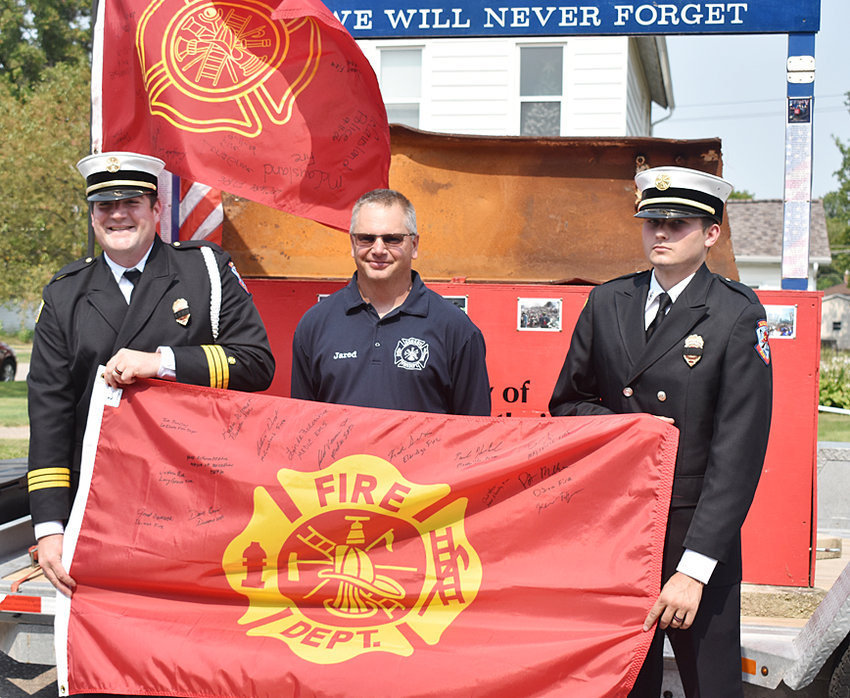 Durant Fire Chief Jared Semsch (middle) is pictured with the flag he signed as the Scott County 9/11 memorial parade came to Durant Sept. 11.