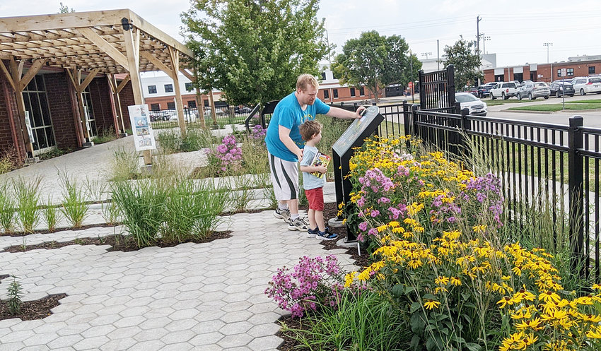In September, Patrick Slessor, pastor at Grace United Church of Christ in Wilton, and his son Lachlan read information about the Wilton Public Library's reading garden, which is planted with native Iowa plants, and is intended to attract butterflies and other pollinators. After opening in the summer when construction was complete on the roughly $278,000 project, several paths and signs have been added, taking visitors on informational journeys while they visit and interact with the space. Several summer and fall programs were held in the new outdoor attraction, with more to come next year.