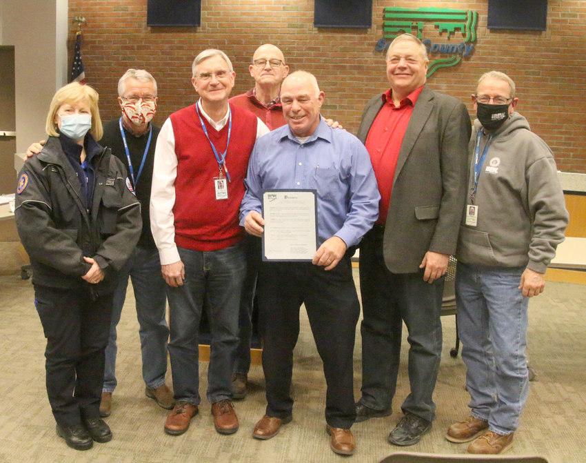 County officials on Jan. 20 present Marty O'Boyle with a resolution thanking him for countywide service during his three terms as Eldridge mayor. Surrounding O'Boyle, from left: Medic director Linda Fredericksen, supervisors Tony Knobbe, Ken Beck, Ken Croken, John Maxwell and Brinson Kinzer.