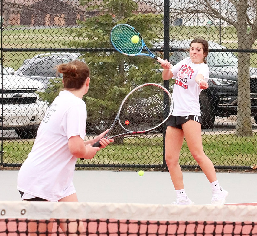 With senior Megan Reese watching closely, Lancer freshman Olive Khoury returns a serve in their No. 1 doubles match against Davenport Central.