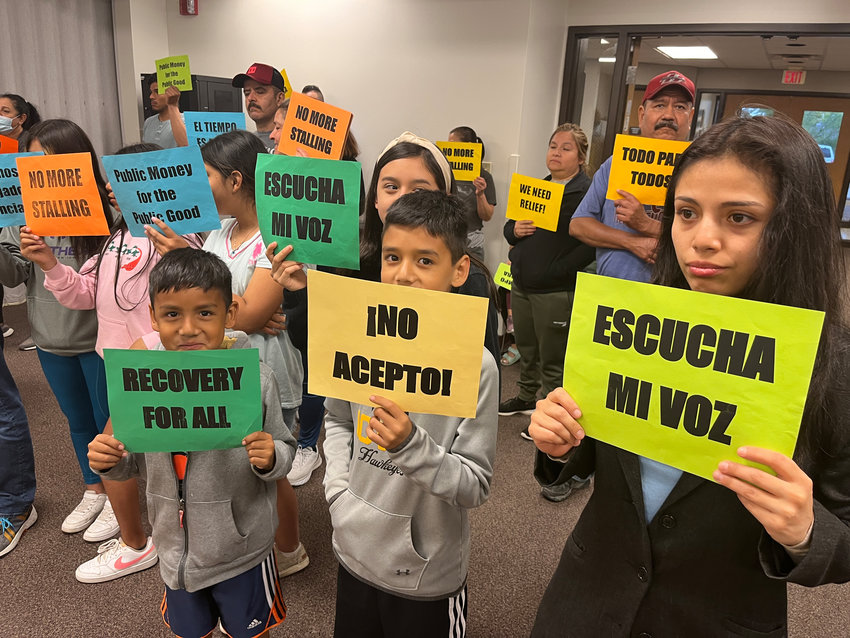 Eschucha Mi Voz members held up signs during public comment at the West Liberty City Council meeting Tuesday, May 17, at the community center.