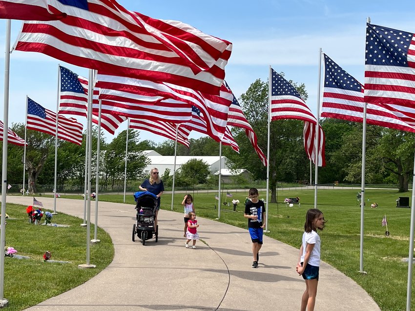 The Rollo and Jaimie  Galvan family of West Liberty takes a casual walk through the Oak Ridge Cemetery identifying local military personnel  including children Isaiah, Karli, Maeli and Gia as they walk through the  Avenue of Flags after the Memorial Day Service Monday.