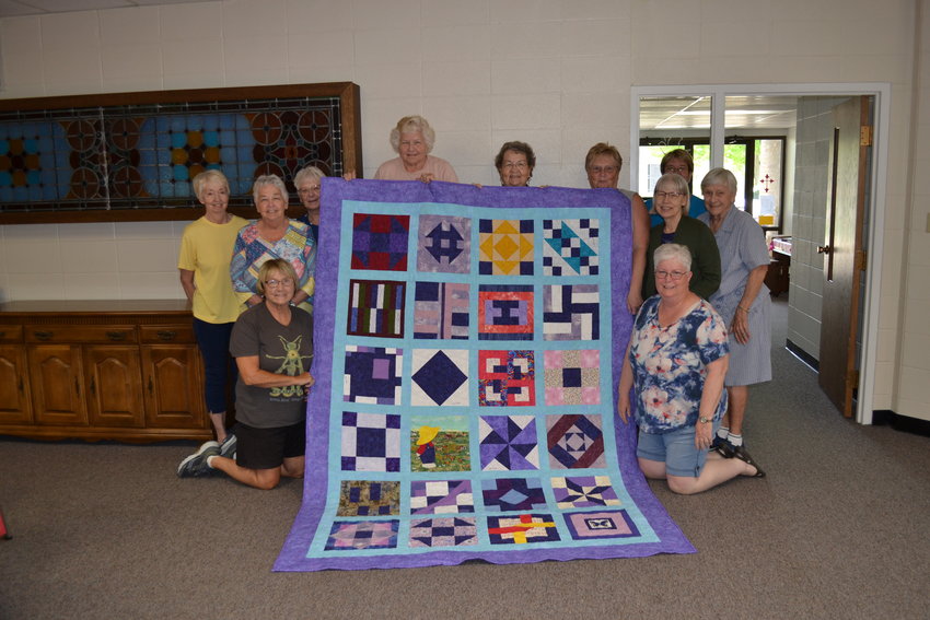 Quilters pose with the quilt that will be auctioned off during the Weekend For The Fair Saturday, June 4.