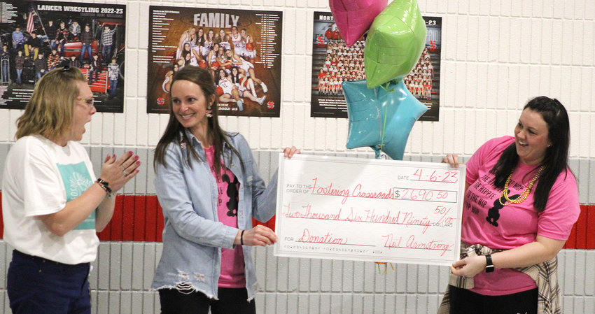Elise Ward reacts as Emily Scott and Quinn Leathers present her with a check for $2,690.50 raised by students.