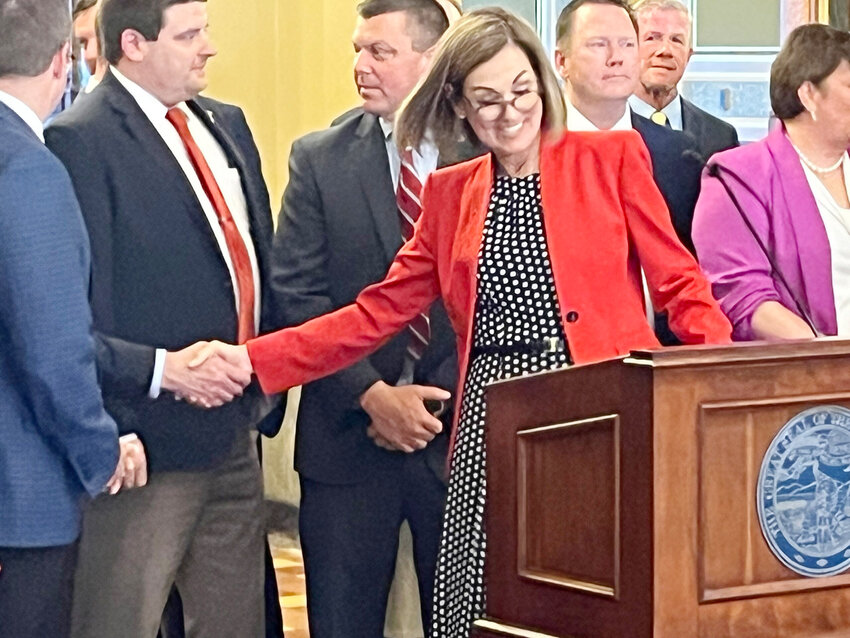 Gov. Kim Reynolds shakes hands with House Speaker Pat Grassley before signing property tax legislation into law May 4, 2023.