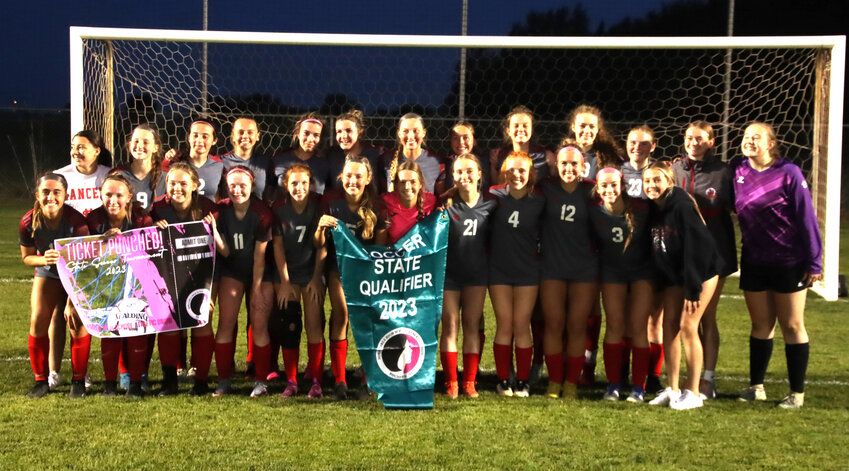 The North Scott girls' soccer team poses with their state qualifier pennant and &quot;ticket punched&quot; poster.