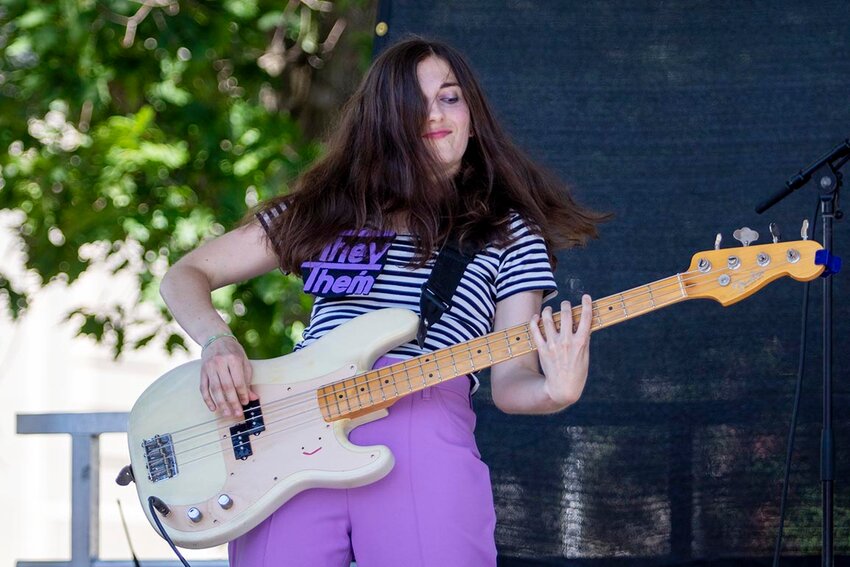 Miss Christine playing their bass guitar at a local festival.