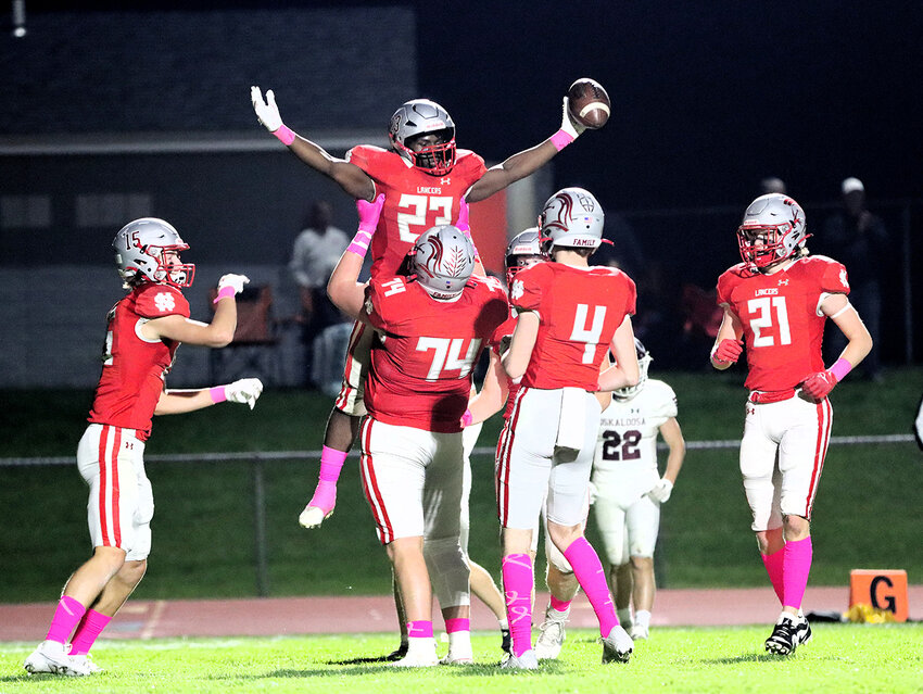 Dawson Rheingans (74) lifts up Jerrod Lee (23) and celebrates with Kye Smith (15), Carson Lage (4) and Will Schneckloth (21) during Friday night's blowout win over Oskaloosa.