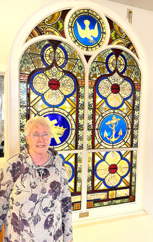 Pastor Paddy Leggins Druhl in front of an historic stained glass piece inside the West Liberty United Methodist Church.