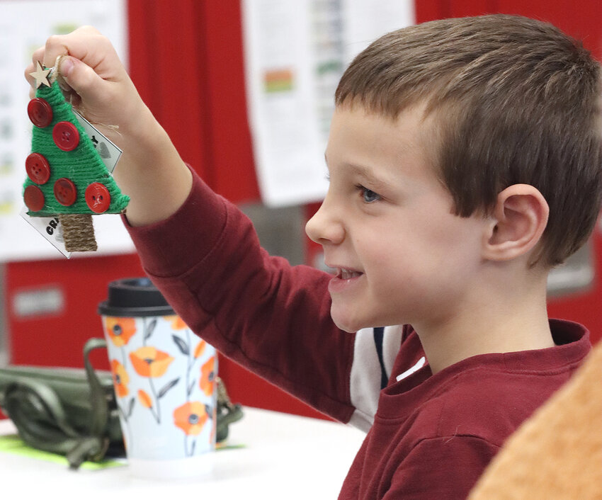 Teagan Merten shows off his ornament during a crafting session.