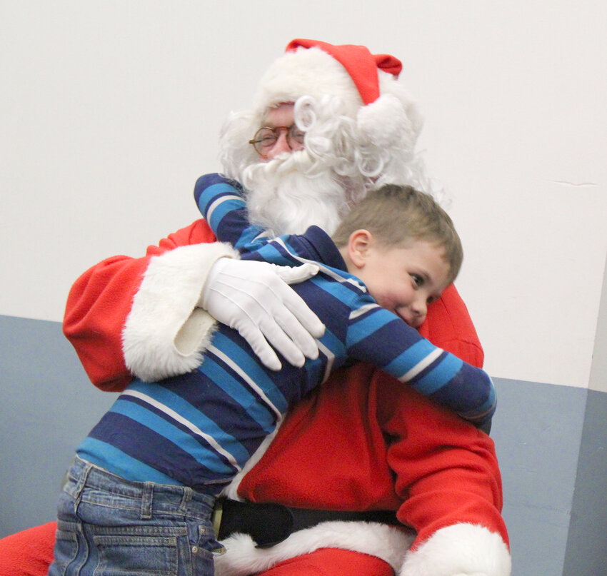 Archer, 6, gives Santa a huge hug during Shop with a Cop, Thursday, Dec. 14, in the Wilton Community Center. Photo by Jacob Lane